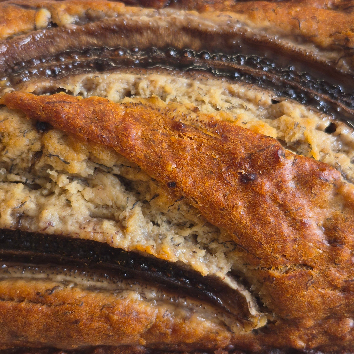 A close-up of a banana bread loaf showing its golden-brown crust and soft, moist banana layers.